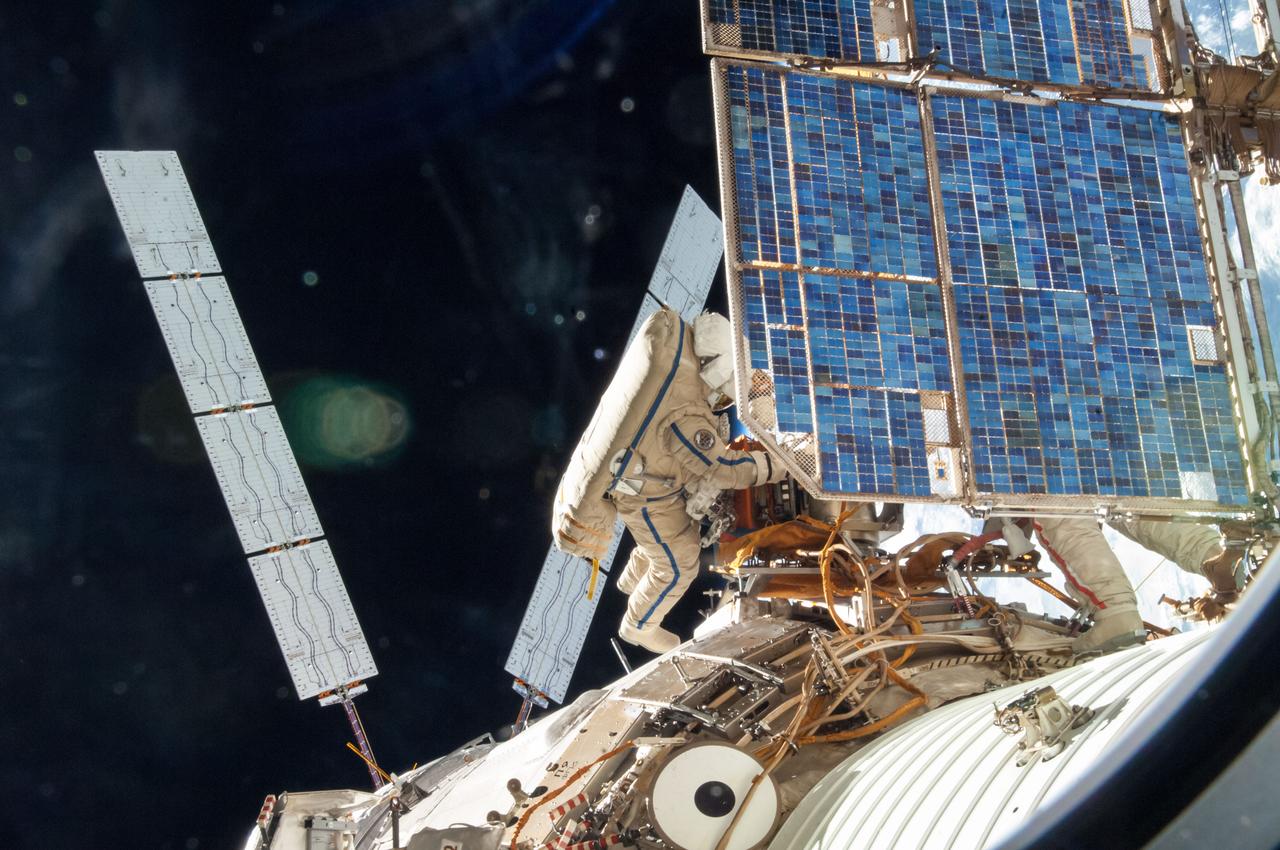 ISS040-E-099266 (18 Aug. 2014) --- Russian cosmonauts Oleg Artemyev (blue stripes) and Alexander Skvortsov (red stripes, mostly obscured), both Expedition 40 flight engineers, attired in Russian Orlan spacesuits, participate in a session of extravehicular activity (EVA) in support of science and maintenance on the International Space Station. During the five-hour, 11-minute spacewalk, Artemyev and Skvortsov deployed a small science satellite, retrieved and installed experiment packages and inspected components on the exterior of the orbital laboratory. Solar arrays wings on the "Georges Lemaitre" Automated Transfer Vehicle-5 (ATV-5) docked to the Zvezda Service Module are visible at left.