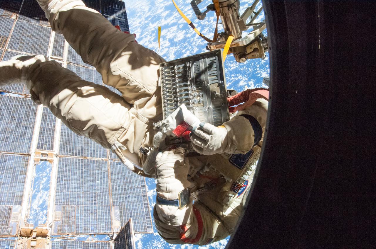 ISS040E099355 (08/18/2014) --- Russian cosmonaut Alexander Skvortsov (red stripes), Expedition 40 flight engineer, attired in a Russian Orlan spacesuit outside the International Space Station, participates in a session of extravehicular activity (EVA) number 39 in support of science and maintenance. The Solar array is visible in the background.