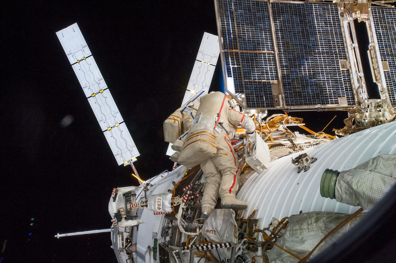 ISS040E099874 (08/18/2014) --- Cosmonauts Alexander Skvortsov (red stripe - foreground) and Oleg Artemyev (blue stripe - background), Expedition 40 flight engineers, move to the Russian Service Module for repairs during International Space Station Russian EVA 39 on Aug. 18, 2014.