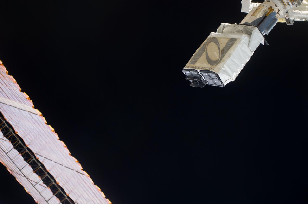 ISS040-E-102410 (20 Aug. 2014) --- In the grasp of the Japanese robotic arm, the CubeSat deployer is about to release a pair of NanoRacks CubeSat miniature satellites. The Planet Labs Dove satellites that were carried to the International Space Station aboard the Orbital Sciences Cygnus commercial cargo craft are being deployed between Aug. 19 and Aug. 25. A section of the station solar array wings is at left.