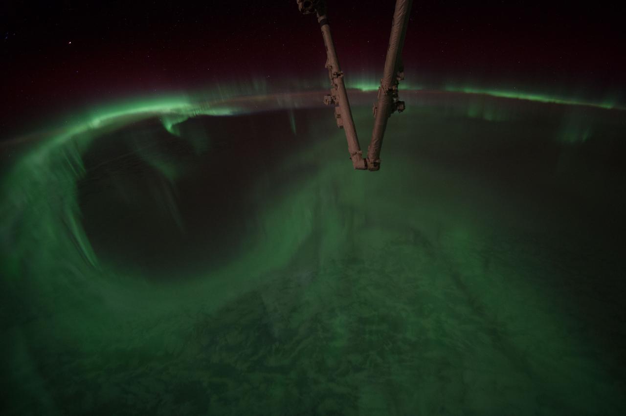 Earth Observation taken during a night pass by the Expedition 40 crew aboard the International Space Station (ISS).  Folder lists this as: Aurora. Part of Space Station Remote Manipulator System (SSRMS) arm is visible.