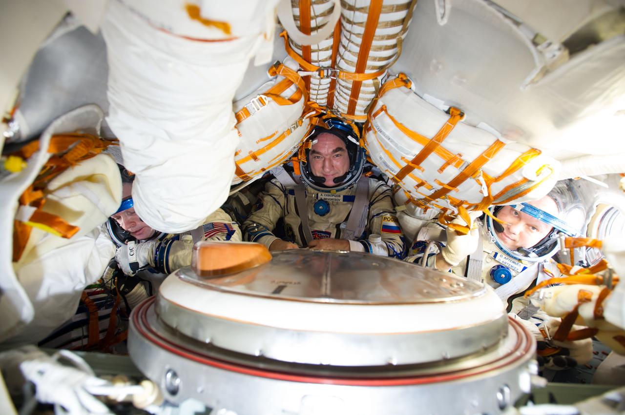 ISS040-E-123151 (2 Sept. 2014) --- Russian cosmonaut Alexander Skvortsov (center), Expedition 40 flight engineer and Soyuz commander; along with NASA astronaut Steve Swanson (left), Expedition 40 commander; and Russian cosmonaut Oleg Artemyev, flight engineer, attired in Russian Sokol launch and entry suits, conduct a standard suit leak check in the Soyuz TMA-12M spacecraft in preparation for their return to Earth scheduled for Sept. 10, 2014.