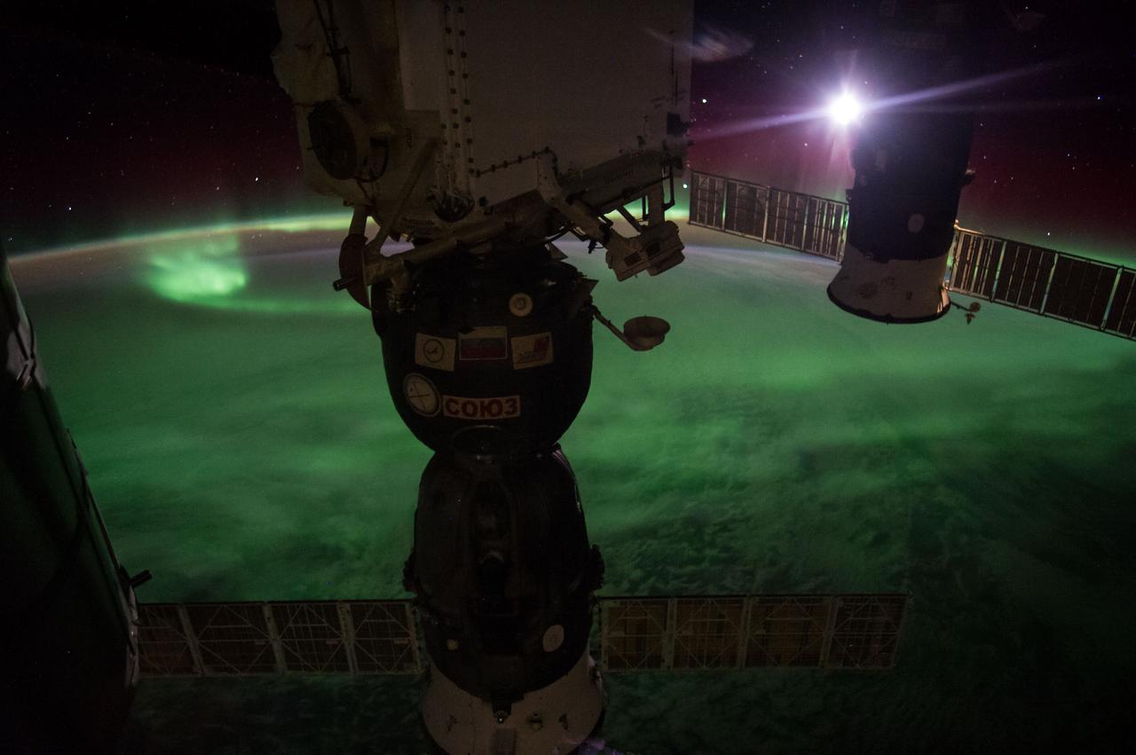 Earth Observation taken during a night pass by the Expedition 40 crew aboard the International Space Station (ISS). Folder lists this as: New Zealand Aurora night pass. Docked Soyuz and Progress spacecraft are visible. On crewmember's Flickr page - The Moon, about to dive into a glowing ocean of green᥿9.