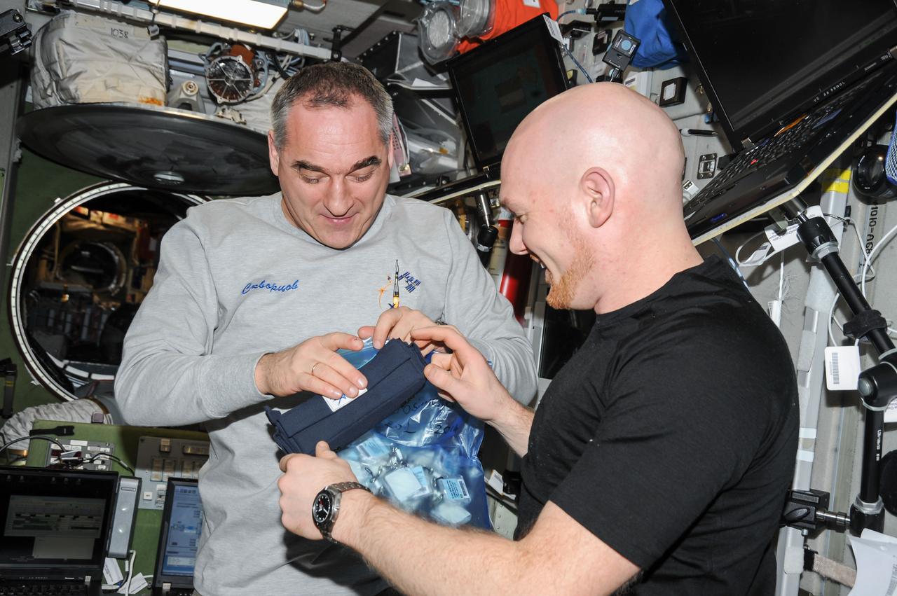 ISS040-E-130025 (9 Sept. 2014) --- European Space Agency astronaut Alexander Gerst (right) and Russian cosmonaut Alexander Skvortsov, both Expedition 40 flight engineers, work with a package of dosimeters in the Zvezda Service Module of the International Space Station.