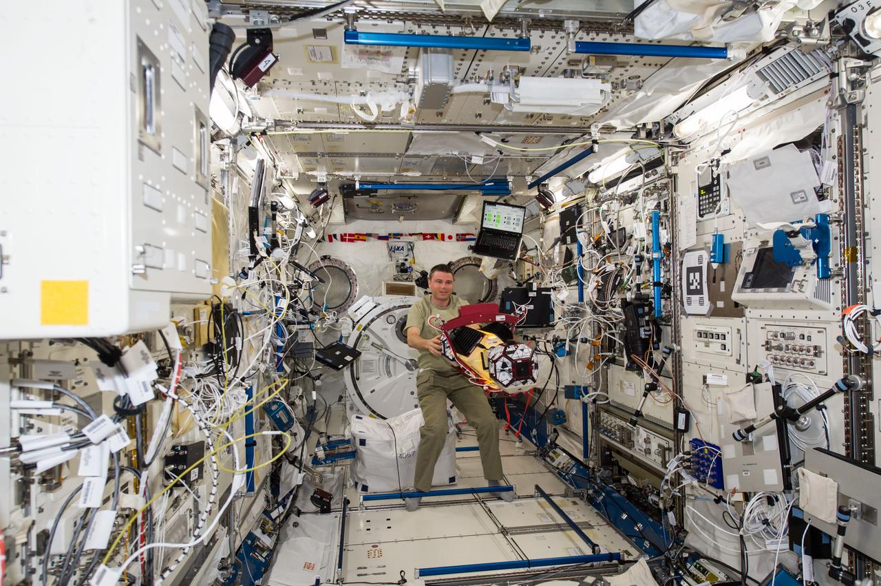 ISS040-E-139549 (9 Sept. 2014) --- In the International Space Station’s Kibo laboratory, NASA astronaut Reid Wiseman, Expedition 40 crew member, works with the bowling ball-sized satellites known as SPHERES (Synchronized Position Hold Engage Reorient Experimental Satellites) to study how liquids behave inside containers in microgravity. The experiment, named SPHERES-Slosh, maneuvers the tiny satellites similar to an actual spacecraft with an externally mounted tank and observes the interaction between the sloshing fluid and the tank/vehicle dynamics.