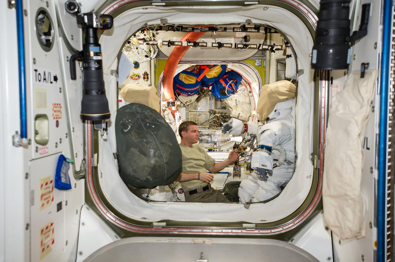 ISS041-E-017023 (19 Sept. 2014) --- NASA astronaut Reid Wiseman, Expedition 41 flight engineer, works with tools and equipment on an Extravehicular Mobility Unit (EMU) spacesuit in the Quest airlock of the International Space Station in preparation for two spacewalks scheduled in October 2014.