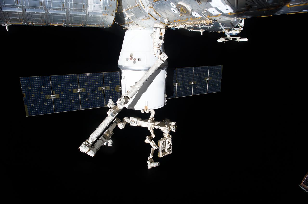 ISS041-E-046450 (29 Sept. 2014) --- An Expedition 41 crew member aboard the International Space Station photographed this view of the SpaceX Dragon cargo ship docked to the nadir port of the Harmony node as the station's Canadarm2 and the Special Purpose Dexterous Manipulator prepare to remove external cargo from Dragon.