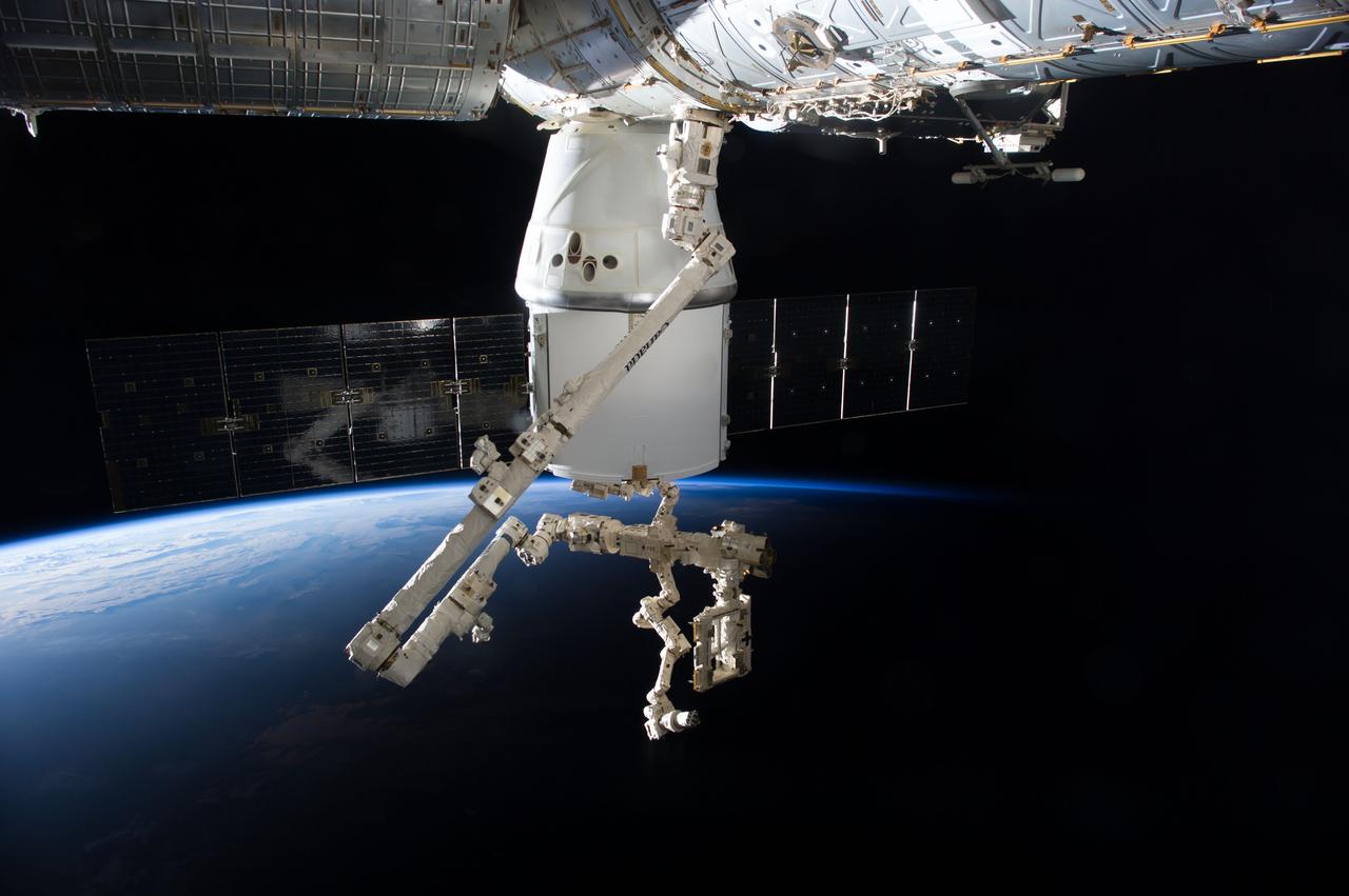 ISS041-E-046700 (29 Sept. 2014) --- An Expedition 41 crew member aboard the International Space Station photographed this view of the SpaceX Dragon cargo ship docked to the nadir port of the Harmony node as the station's Canadarm2 and the Special Purpose Dexterous Manipulator prepare to remove external cargo from Dragon. Earth?s horizon and the blackness of space provide the backdrop for the scene.
