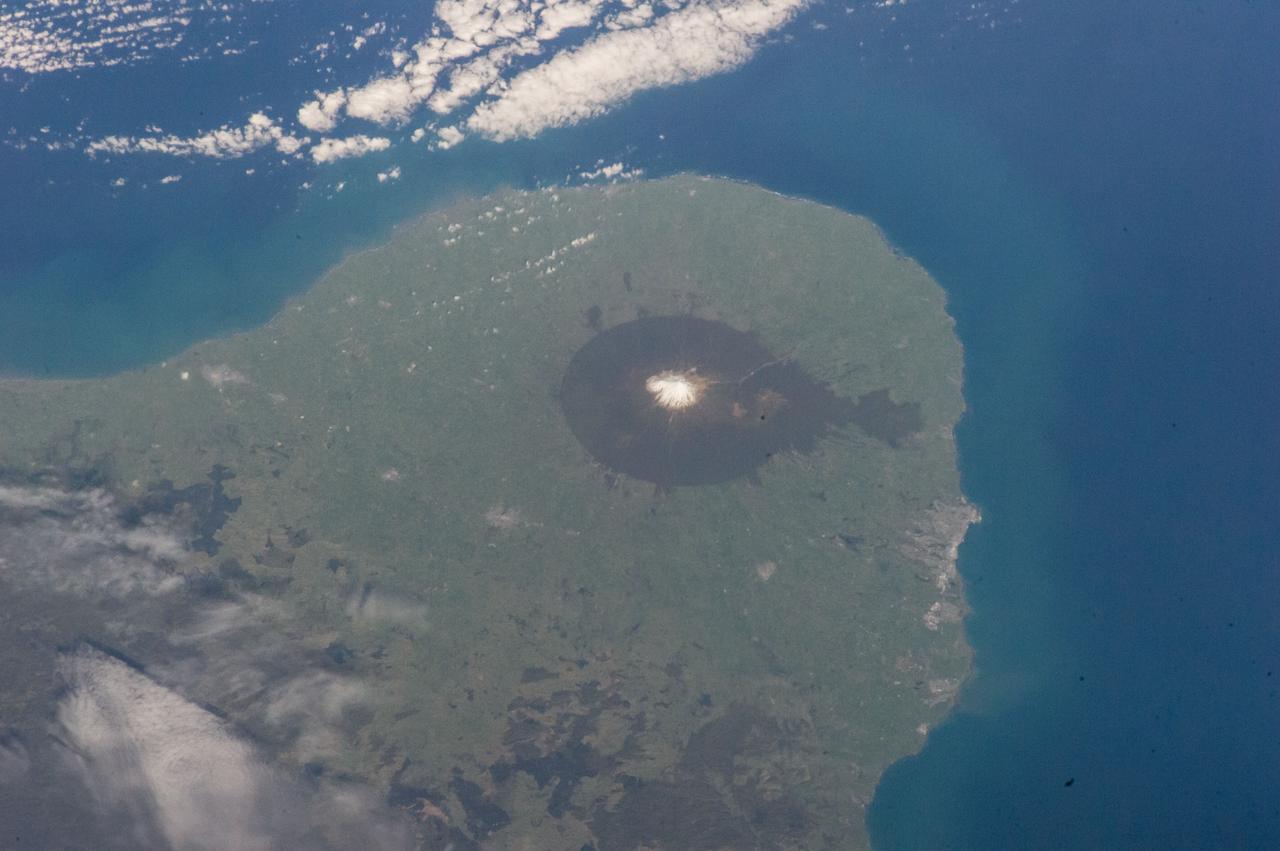 ISS041-E-049111 (30 Sept. 2014) --- One of the Expedition 41 crew members onboard the International Space Station, flying at an altitude of 226 nautical miles, exposed this image of Mount Egmont Volcano, New Zealand, using a focal length setting of 200mm. Sometimes referred to as Mount Taranaki, the land feature is a young stratovolcano that began to form 70,000 years ago, according to volcanists. Located in southwest North Island, New Zealand, Mount Egmont, at 8,261 feet (2,518 meters) is the second tallest volcanic mountain in New Zealand. Perpetually snow-capped, the volcano last erupted in 1755. Mount Egmont has a history of a major size eruption occurring every 340 years, with numerous minor ones in between. The volcano has had three major cone collapses in the last 25,000 years with the last collapse occurring 6,970 years ago. With each collapse, thick layers of ash and lava crumbled into thick, muddy avalanches called lahars. These lahars have reached the coastline 25 miles (40 kilometers) to the west and north of the volcano. Egmont is surrounded by forest, especially on its lower flanks, which is part of a National Park. The pastureland that circles the park is used for dairy farming.