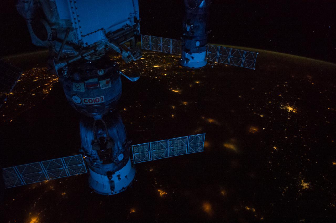 ISS041-E-057060 (1 Oct. 2014) --- One of the Expedition 41 crew members aboard the International Space Station, flying at an altitude of 220 nautical miles, photographed this night panorama of parts of Europe on Oct. 1, 2014.  Kiev, Ukraine is seen near the right edge of the photo in the vertical center. Lights of Constanta, Romania can be seen just below the Russian Progress 56 cargo vehicle docked to the orbital outpost at the top of the frame. The Black Sea is to the left of the Soyuz TMA-13M docked to the station on the left side of the scene. The Sea of Azov is at the right of the bottom portion the Soyuz. Mariupol is near bottom center; and Donetsk, although it appears as a (bottom-most) tiny smudge on the right side of the image, has a population of just under five million. Krasnodar, Russia is in the bottom left corner. Part of Greece is in the top of the image near the solar panel of the Progress, with Thessaloniki and Sofia among the many bright lights. Part of Turkey is in upper left of the land mass visible. Pre-dawn light coming through the atmosphere gives the station hardware a bluish color.