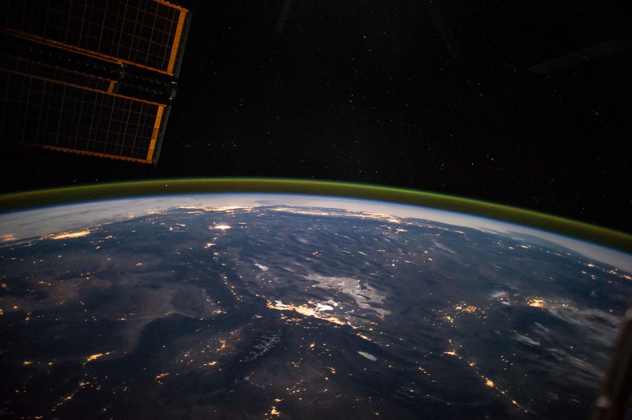 ISS041-E-067595 (6 Oct. 2014) --- This moonlit panorama was shot recently with a wide-angle lens by an Expedition 41 crew member aboard the International Space Station, as they looked southwest from a point over Nebraska. The wide-angle lens shows a huge swath of country that stretches from Portland, Oregon (right) to Phoenix, Arizona (left). The largest string of lights is the Ogden-Salt Lake City-Provo area (lower center) in Utah. The Los Angeles and San Francisco metropolitan regions, and the cities of the central valley of California (Bakersfield to Redding) stretch across the horizon. The green airglow layer always appears in night images. Moonlight shows the red tinge of the space station?s solar arrays top left. Moonlight emphasizes the broader-scale geological zones. Nevada?s short, dark, parallel mountain ranges of the basin and range geological province (center) contrast with the expanses of flat terrain of the Colorado Plateau (left) in Colorado, Arizona, Utah and New Mexico. The near-full moon even reveals the vast dry lake bed known as the Bonneville Salt Flats. The black line of the Sierra Nevada marks the edge of California?s well-lit central valley (directly below the San Francisco Bay area).