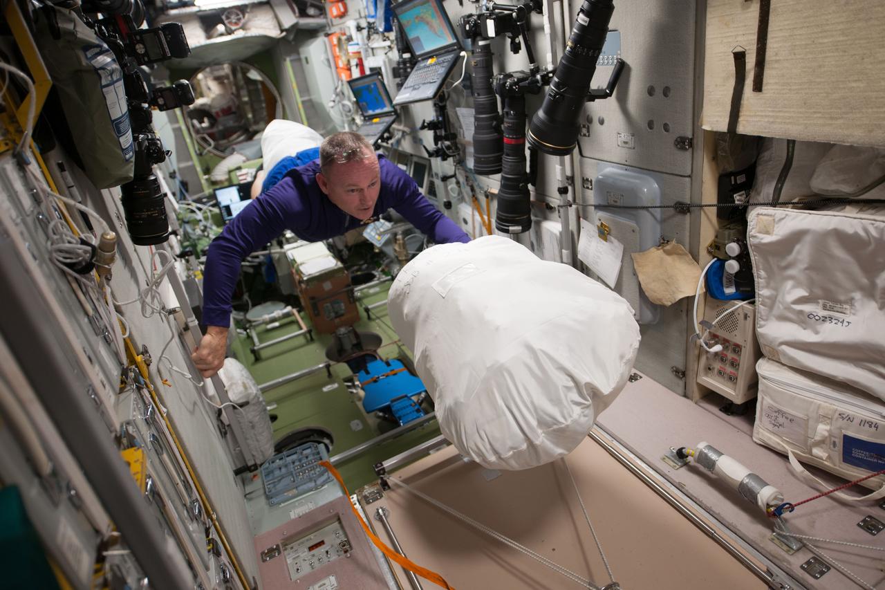 Commander Barry Wilmore floats through the Zvezda Service Module (SM) with a full Jettison Stowage Bag. Image was released by astronaut on Instagram.