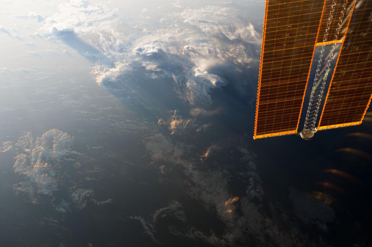 ISS042E021548 (12/03/2014) --- Voluminous clouds envelope the Earth at dusk in this image taken by the crew of the International Space station. An arm of the stations massive solar array frames the Earth observation.