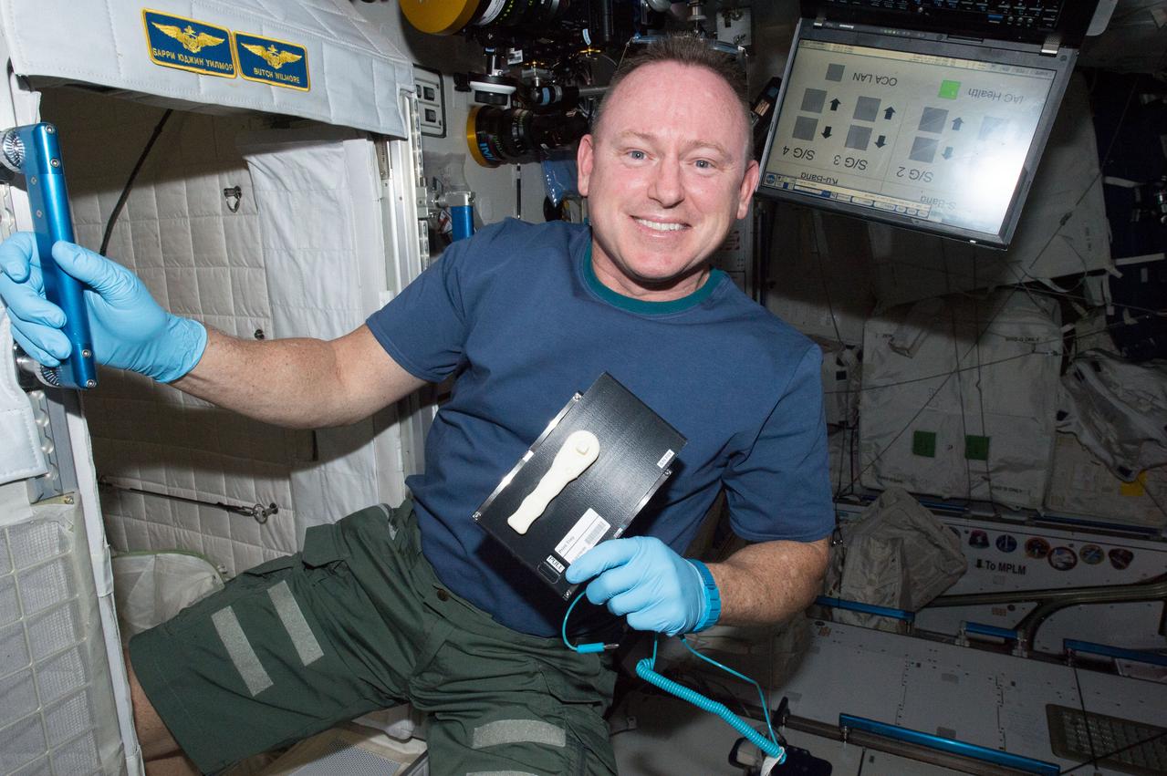 iss042e046041 (12/16/14) --- NASA Astronaut Barry (Butch) Wilmore holds a 3-D printed ratchet wrench and plate from the new 3-D printer aboard the International Space Station. The printer completed the first phase of a NASA technology demonstration by printing a tool with a design file that was transmitted from the ground to the printer.