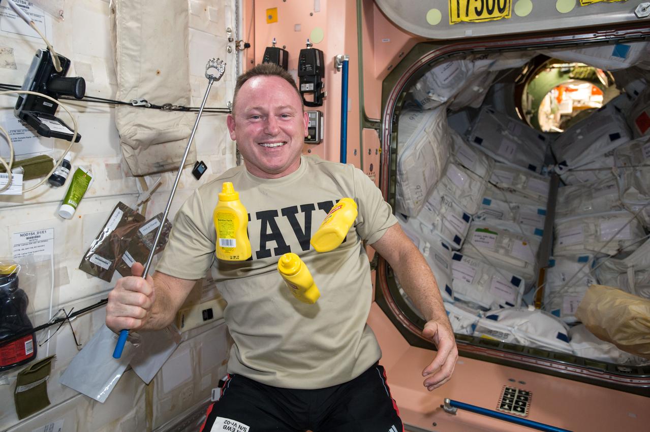 ISS042E136080 (01/15/2015) --- US astronaut Barry "Butch" Wilmore, Expedition 42 Commander on the International Space Station, is photographed in the Unity Node 1 with three floating mustard bottles recently delivered to the ISS. This picture was taken by his fellow US astronaut Terry Virts.