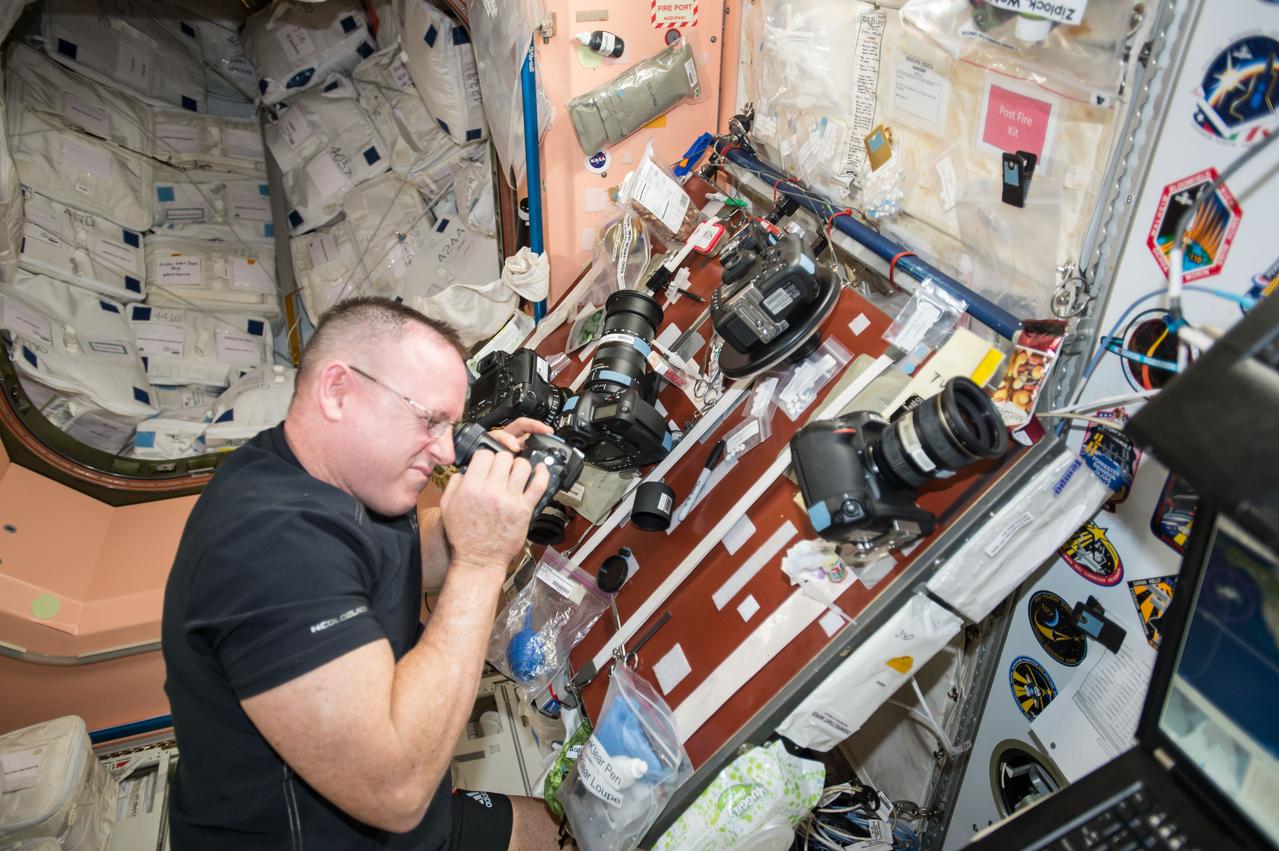 ISS042E182382 (01/25/2015) ---US astronaut Barry "Butch" Wilmore inspects one the cameras aboard the International Space Station Jan. 25, 2015, in preparation for another photo session of station experiments. Barry is the Commander of  Expedition 42.