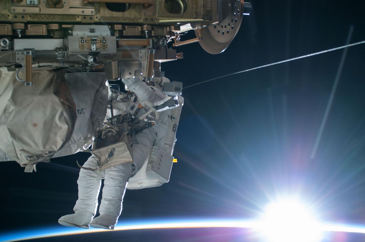 ISS042E283203 (02/21/2015) – NASA astronaut Terry Virts Flight Engineer of Expedition 42 on the International Space Station is seen working to complete a cable routing task while the sun begins to peak over the Earth’s horizon on Feb. 21 2015. Virts and fellow astronaut Barry “Butch” Wilmore completed a 6-hour, 41-minute spacewalk routing more than 300 feet of cable as part of a reconfiguration of the station to enable U.S. commercial crew vehicles under development to dock to the space station in the coming years.
