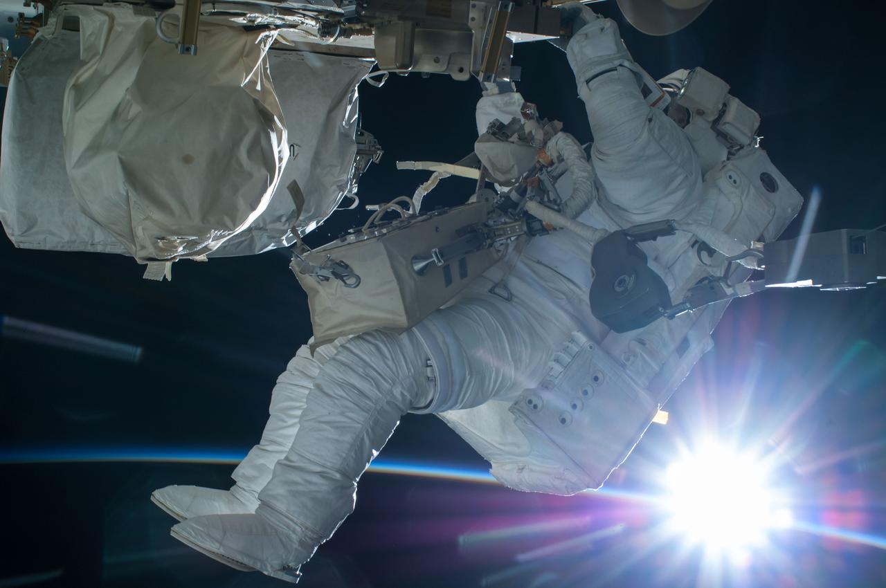 Flight engineer Terry Virts, Extravehicular crewmember 2 (EV2), translates External Stowage Platform 2 (ESP2) at the close of Extravehicular Activity 29 (EVA 29). An orbital sunrise provides the backdrop for this image, which was released by Virts on Twitter.