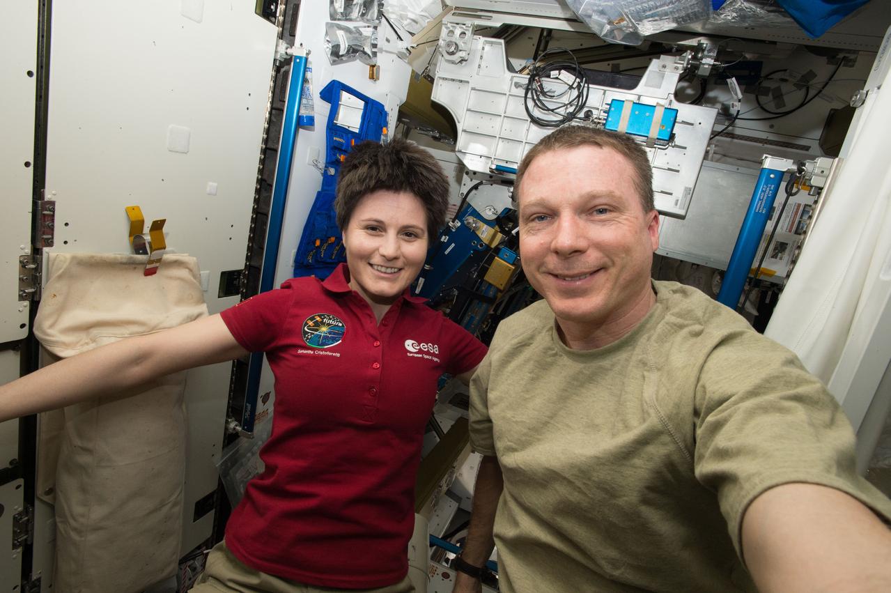    ESA Astronaut Samantha Cristoforetti and Expedition 43 commander Terry Virts pose for a photo in front of Crew Quarters (CQ) after hair cut. 