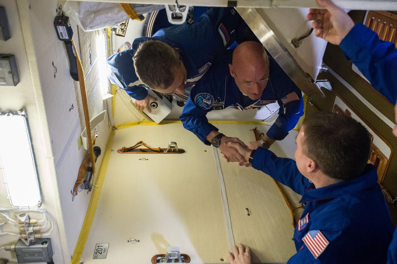 ISS043E056048 (03/28/2015) --- NASA astronaut Scott Kelly (top right) emerges through the hatch from the Soyuz spacecraft after launching from the Earth earlier to be welcomed by Expedition 43 commander and NASA astronaut Terry Virts aboard the International Space Station on Mar. 28, 2015. Russian cosmonaut Mikhail Kornienko (top left) is next out of the hatch to be welcomed aboard. These two will begin a unique one-year mission on board the station to study longer time frames in space to prepare for the journey to Mars.