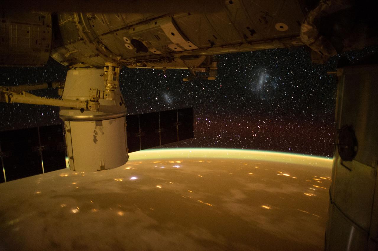 ISS043E125469 (04/18/2015) --- A dying sun turns the Earth gold with cities sparkling to match the stars that spread out from the International Space Station. NASA astronaut Terry Verts tweeted this wondrous image  with the attached comment about the stars: " See those light clusters? (center sky left and right)They are Magellanic clouds, a duo of dwarf galaxies seen from the southern hemisphere".