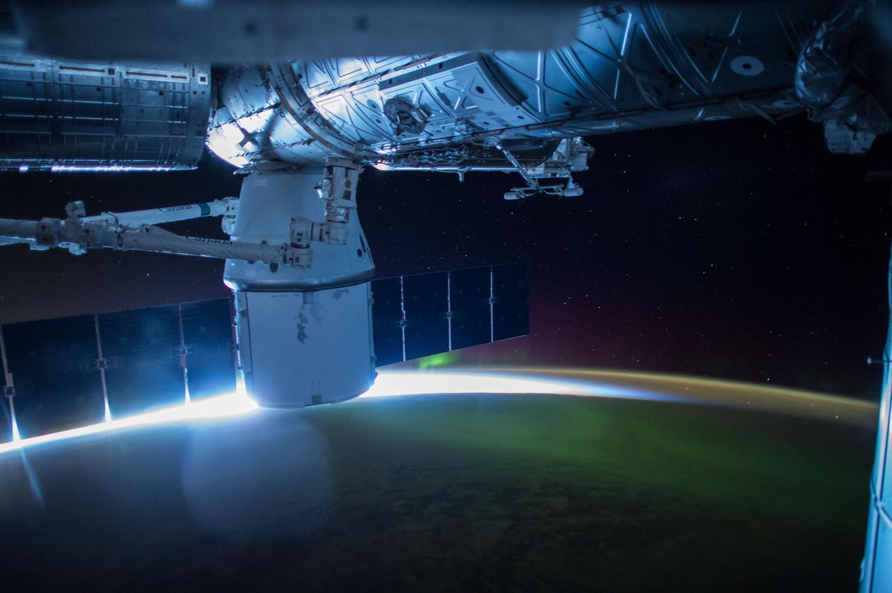 ISS043E125565 (04/18/2015) --- This night image from the International Space Station shows the sun beginning to peak above the horizon sparkling through a green Aurora and reflecting a blue reflection off the station on Apr. 18, 2015 during Expedition 43.