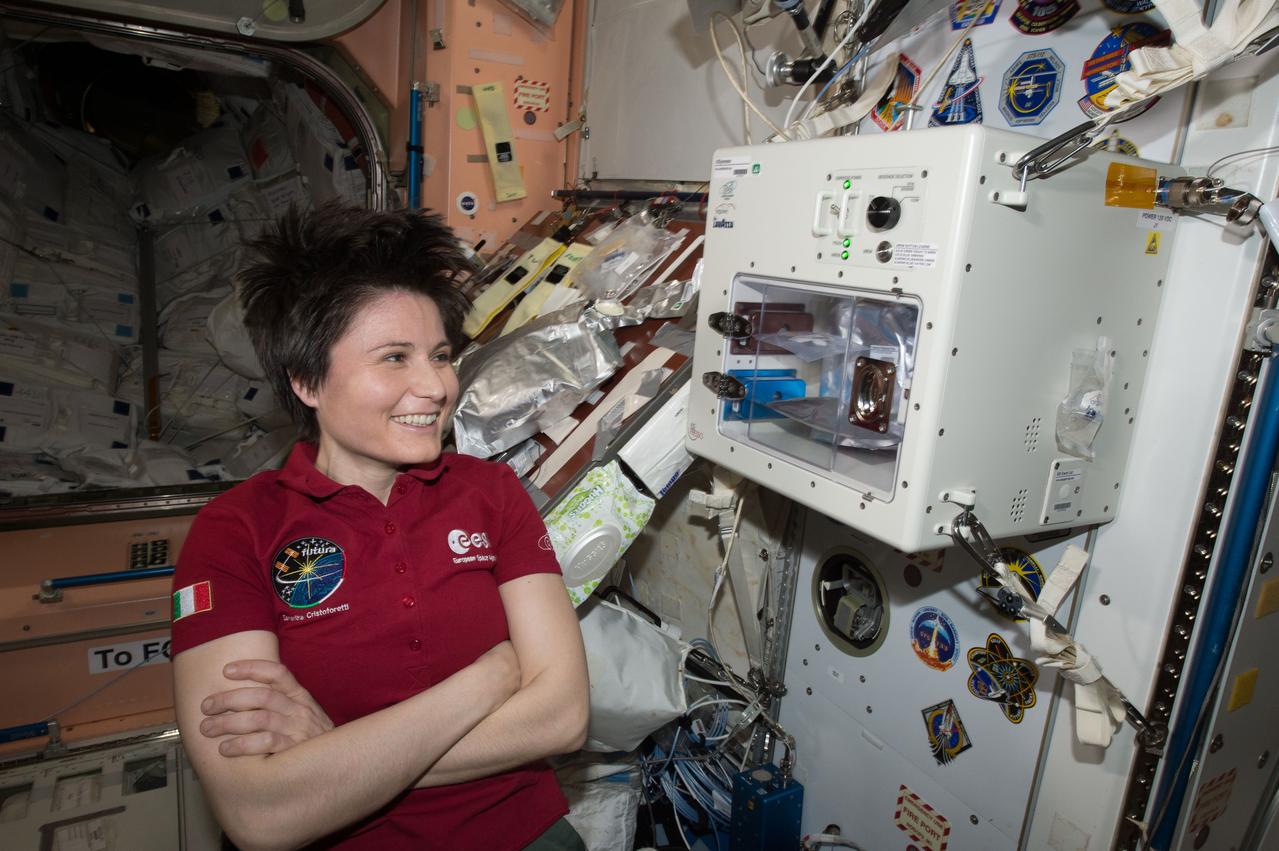 ISS043E160068 (05/03/2015) --- ESA (European Space Agency) astronaut Samantha Cristoforetti waits next to the newly installed ISSpresso machine. The espresso device allows crews to make tea, coffee, broth, or other hot beverages they might enjoy.