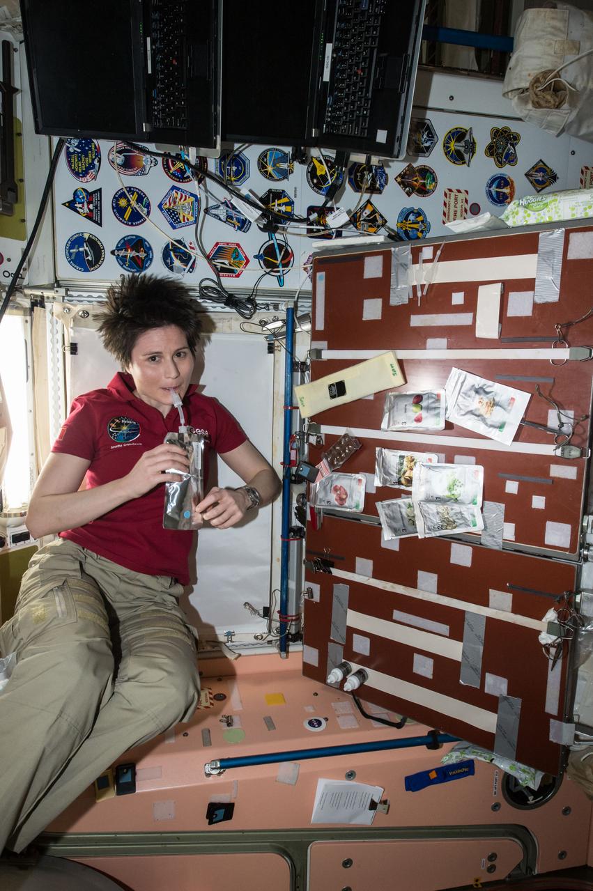 ISS043E162881 (04/27/2015) --- ESA (European Space Agency) astronaut Samantha Cristoforetti seen taking a drink in the Unity module aboard the International Space Station Apr. 27. 2015. The crew’s food galley is located in Unity and there are several food packets visible to the right.