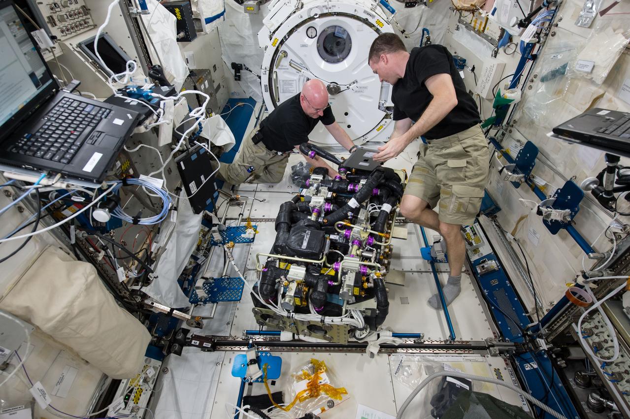ISS043E181459 (05/07/2015) – NASA astronauts Scott Kelly (left) and Terry Virts (right) work on a Carbon Dioxide Removal Assembly (CDRA) inside the station’s Japanese Experiment Module. The CDRA system works to remove carbon dioxide from the cabin air, allowing for an environmentally safe crew cabin.