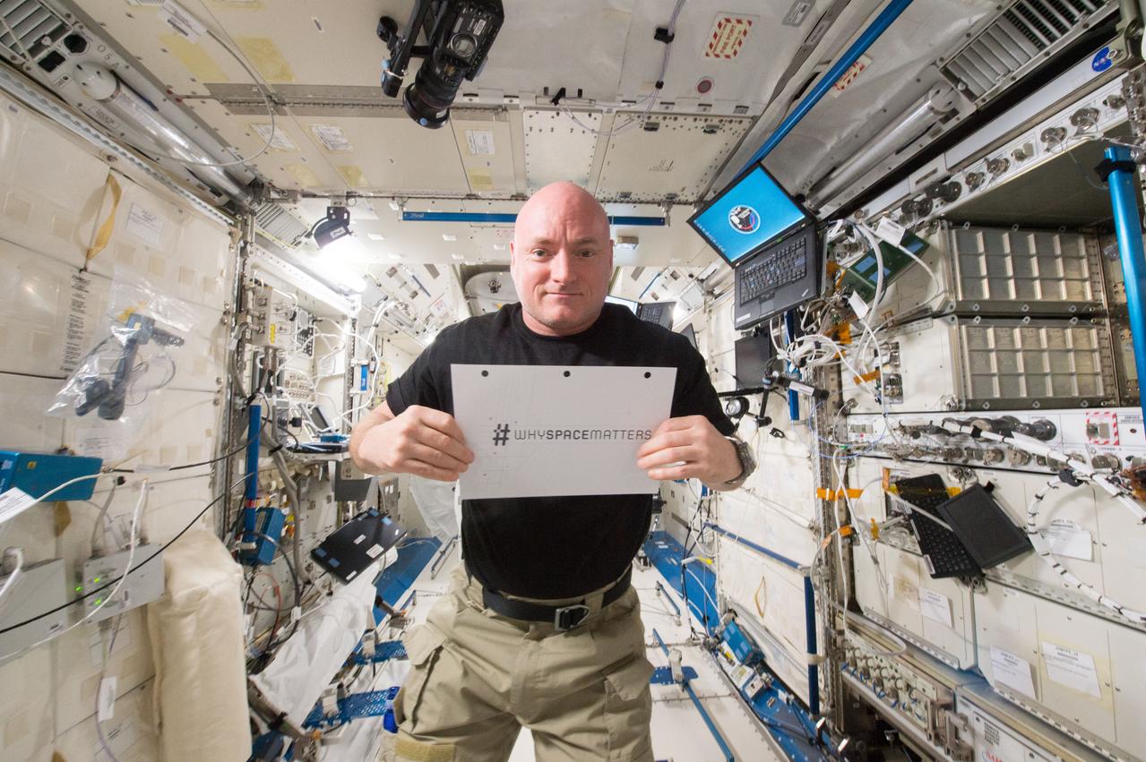 ISS043E294202 (06/10/2015) --- NASA astronaut Scott Kelly is photographed in the Japanese Experiment Module (JEM) holding a sign with the hashtag #whyspacematters. NASA and the United Nations Office for Outer Space Affairs (UNOOSA) have launched a global photography competition to highlight how the vantage point of space helps us better understand our home planet, improve lives, and safeguard our future by aiding sustainable development on Earth.