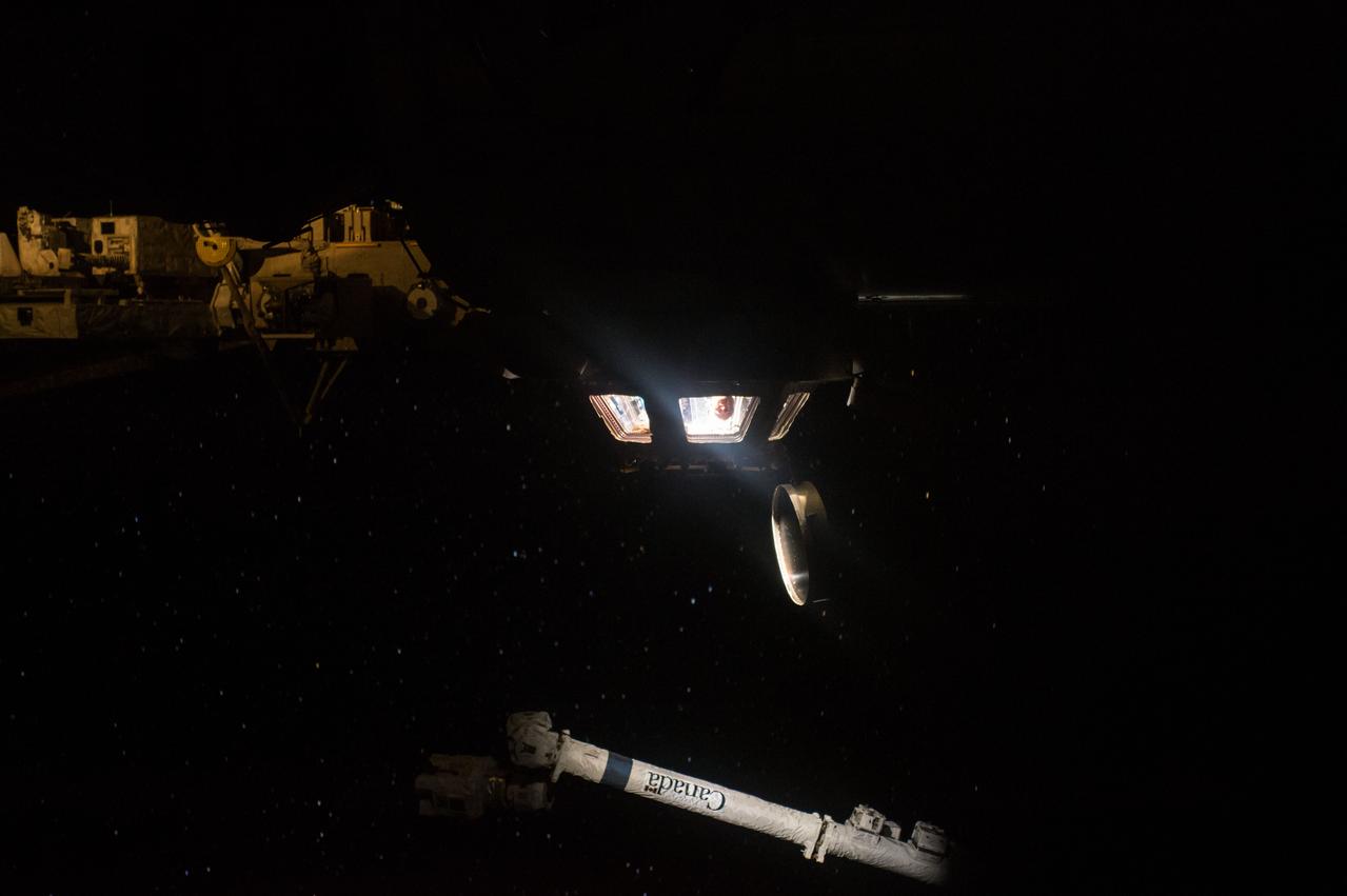 ISS045E002596 (09/14/2015) --- Expedition 45 commander Scott Kelly is seen peeking out of the space station’s Cupola module which provides a 360-degree view of the Earth below. The module is also used for robotics operations, including controlling the station’s main robotic device Canadarm2, seen below the Cupola.