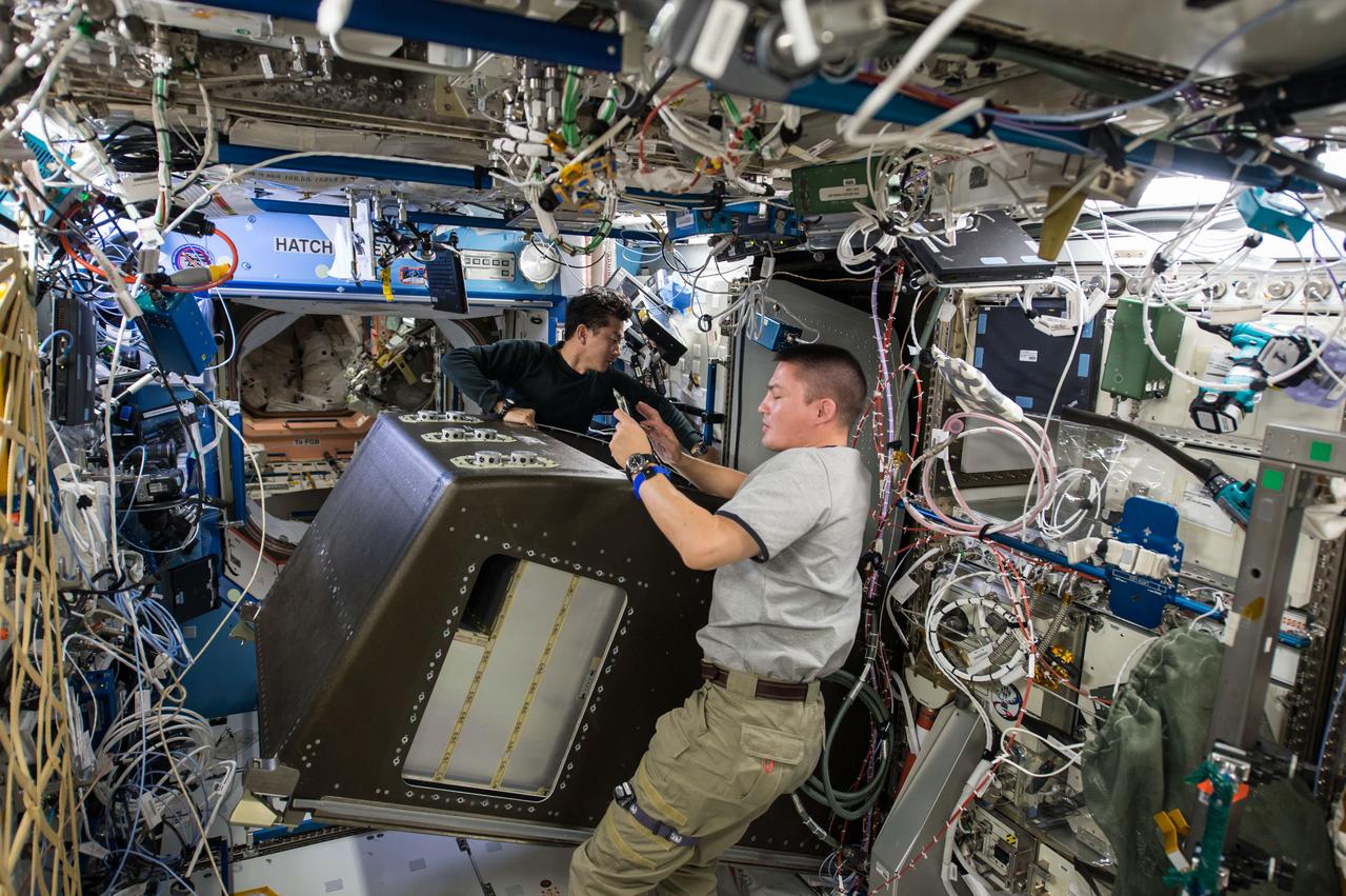 ISS045E019087 (09/18/2015) --- Japanese astronaut Kimiya Yui (left) and NASA astronaut Kjell Lindgren (right) work on removing items from a storage rack located inside the International Space Station’s Destiny laboratory. The pair are making room for new communications hardware that will be used for future visiting vehicles arriving at the space station, including the new U.S. commercial crew vehicles currently in development.