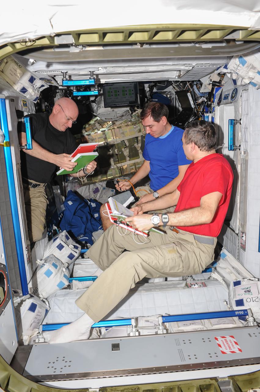 ISS045E020492 (09/22/2015) --- NASA astronaut Scott Kelly (Left) and Russian cosmonauts Sergey Volkov (Center) and  Mikhail Kornienko (right) review procedures aboard the International Space Station.