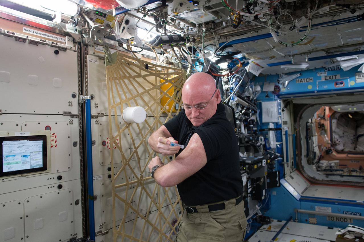 ISS045E028258 (09/24/2015) --- NASA astronaut Scott Kelly gives himself a flu shot for an ongoing study on the human immune system. The vaccination is part of NASA’s Twins Study, a compilation of multiple investigations that take advantage of a unique opportunity to study identical twin astronauts Scott and Mark Kelly, while Scott spends a year aboard the International Space Station and Mark remains on Earth.