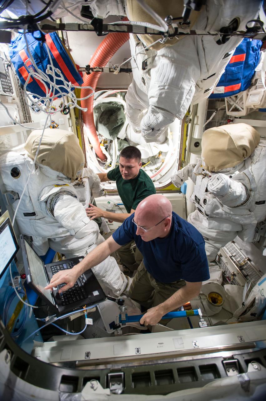 ISS045E050652 (10/07/2015) --- US astronauts Scott Kelly (bottom)and Kjell Lindgren (top) are counting down to a pair of spacewalks, now targeted for Oct. 28 and Nov. 6. The duo serviced their spacesuits replacing lithium batteries, checking their gloves and verifying power to video cameras. On the first spacewalk, the spacewalkers will lubricate the tip of the robotic arm Canadarm2, route power cables and place a thermal shroud over the Alpha Magnetic Spectrometer. During the second spacewalk, Kelly and Lindgren will refill coolant reservoirs and configure the port truss cooling system back to its original configuration after repair work completed back in 2012.