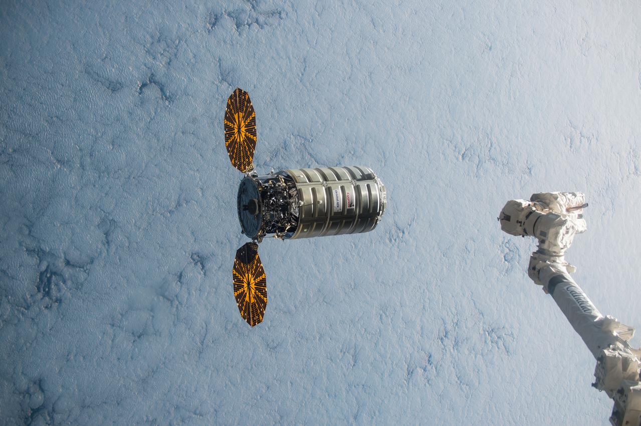 ISS045e176110 (12/09/2015) --- Using the International Space Station’s robotic arm, Canadarm2 (right) NASA Flight Engineer Kjell Lindgren prepares to capture Orbital ATK’s Cygnus cargo vehicle Dec. 09, 2015. The space station crew and the robotics officer in mission control in Houston will position Cygnus for installation to the orbiting laboratory’s Earth-facing port of the Unity module. Among the more than 7,000 pounds of supplies aboard Cygnus are numerous science and research investigations and technology demonstrations, including a new life science facility that will support studies on cell cultures, bacteria and other microorganisms; a microsatellite deployer and the first microsatellite that will be deployed from the space station; several other educational and technology demonstration CubeSats; and experiments that will study the behavior of gases and liquids, clarify the thermo-physical properties of molten steel, and evaluate flame-resistant textiles.
