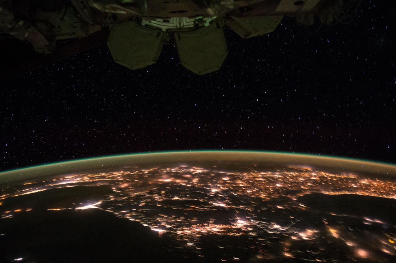 ISS045e176195 (12/05/2015) --- Sparkling City lights are framed by an aurora along the Earths horizon and part of the International Space Station on Dec. 05. 2015 as the station flies around the world at 17500 miles an hour.
