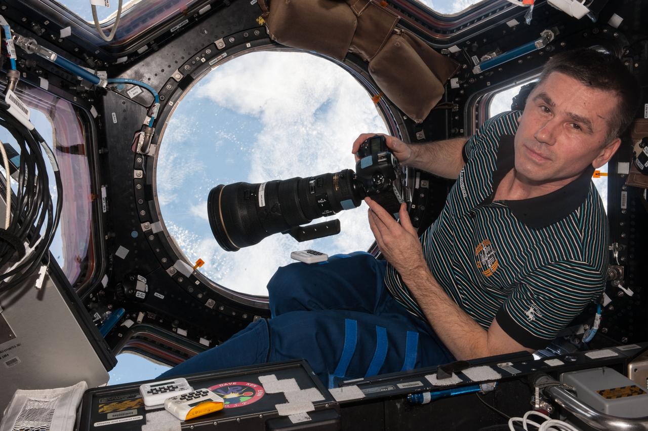 ISS047e001484 (03/05/2016) --- Expedition 47 flight engineer Yuri Malenchenko from Roscosmos is photographed in the International Space Station’s Cupola module preparing to take Earth pictures using a 400 mm lens. The Cupola's 360 degree viewing platform provides optimal views of the Earth below and also contains the control mechanisms for the station’s Canadarm2 robotic arm.