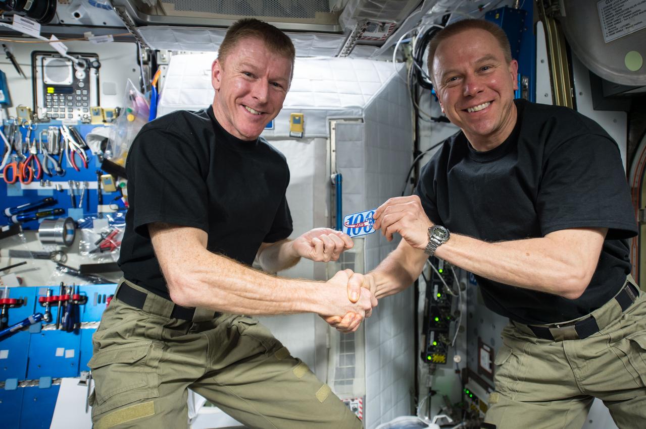 ISS047e017191 (03/24/2016) --- NASA astronaut Tim Kopra (right) presents ESA (European Space Agency) astronaut Tim Peake (left) with a patch to commemorate his 100th day in space on March 24, 2016. Peake, who arrived at the station along with Kopra on Dec. 15, 2015, is on his first spaceflight and was the 221st individual to visit the International Space Station.