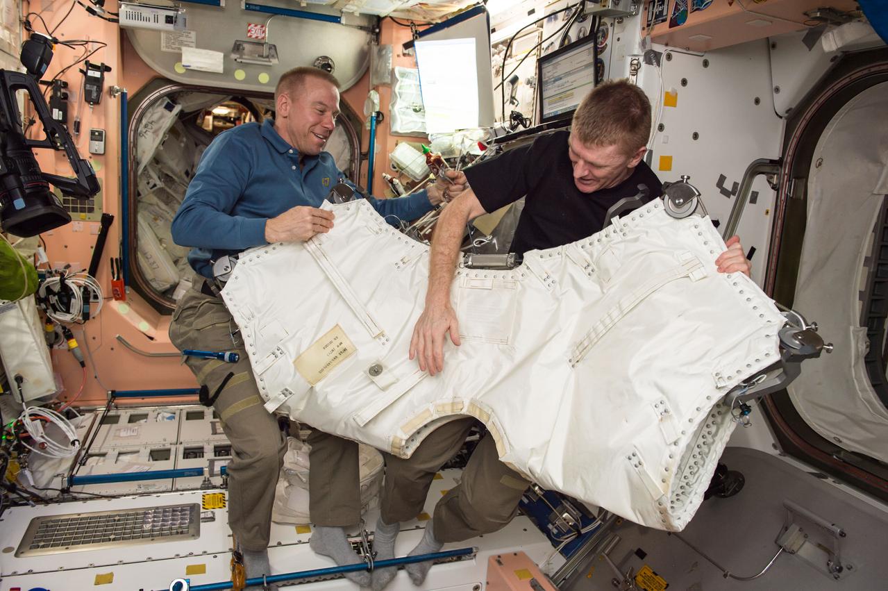 ISS047e028518 (03/26?2016) --- NASA astronaut Tim Kopra, Expedition 47 Commander, and ESA (European Space Agency) astronaut Tim Peake, Expedition 47 Flight Engineer gather hardware to outfit the area between Orbital ATK’s Cygnus cargo vehicle and the Unity Module.