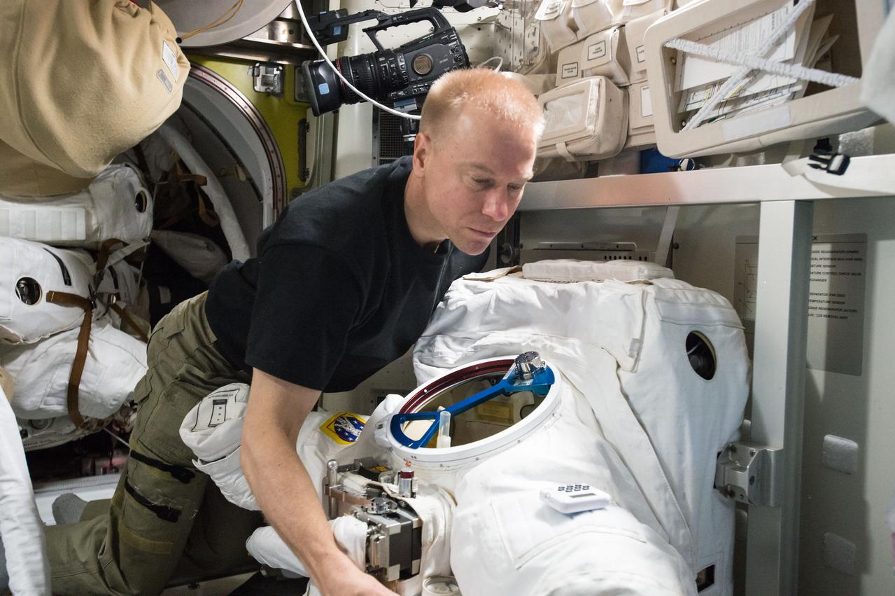 ISS047e032108 (04/01/2016) --- NASA astronaut and Expedition 47 commander Tim Kopra conducts a loop scrub on two U.S. spacesuits inside the Quest airlock. Periodic cleaning and sampling of the spacesuit cooling loops is conducted to ensure the suits are in working order and ready to support future spacewalks.