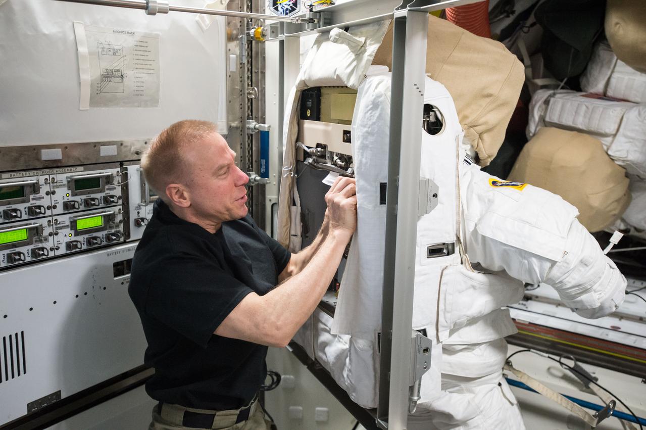 ISS047e048133 (04/01/2016) --- NASA astronaut Tim Kopra prepares a U.S. Extravehicular Mobility Unit (EMU) spacesuit for cooling loop maintenance. Spacesuits on-board the International Space Station get routine maintenance between spacewalks.