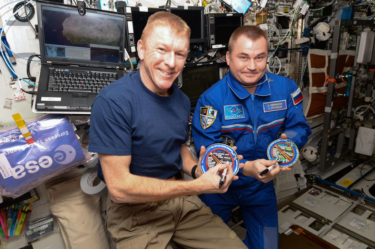 ISS047e050582 (04/09/2016) --- Expedition 47 crew members Tim Peake of ESA (European Space Agency) left, and Alexey Ovchinin of Roscosmos cross their names off the ceremonial “League of Unflown Astronauts” patch. Both are on their first spaceflight and were the 221st and 222nd individuals to visit the International Space Station, respectively.
