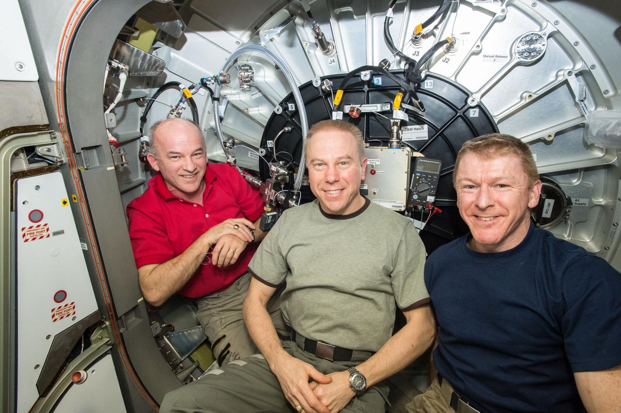 ISS047e135573 (05/28/2016) --- Expedition 47 astronauts Jeff Williams (left) and Timothy Kopra (middle) of NASA, along with ESA (European Space Agency) astronaut Timothy Peake (right) pose in front of the entrance to the Bigelow Expandable Activity Module (BEAM) after successful expansion. NASA Astronaut Jeff Williams and the NASA and Bigelow Aerospace teams working at Mission Control Center at NASA’s Johnson Space Center spent more than seven hours on operations to fill the BEAM with air to cause it to expand.
