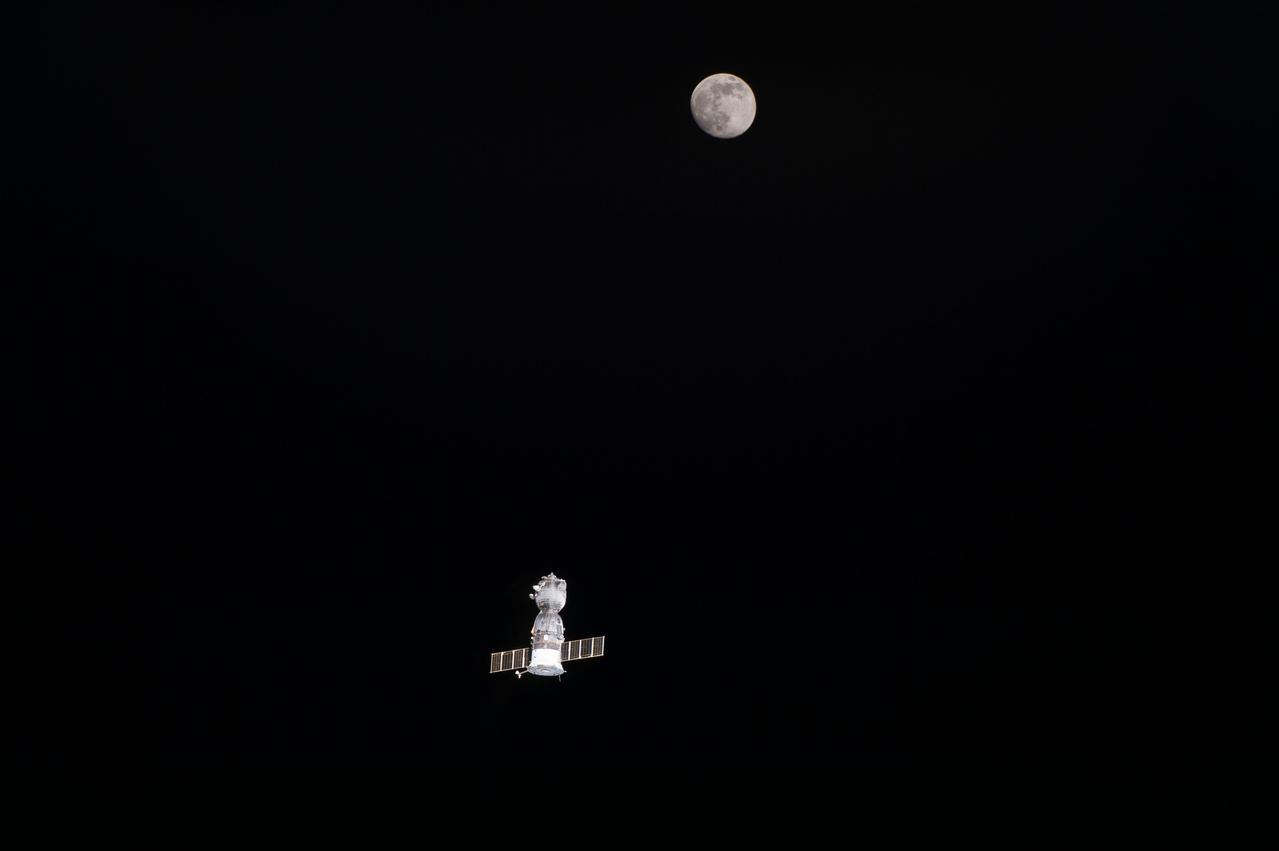 View of the departing Soyuz TMA-19M spacecraft and the nearly full Moon.