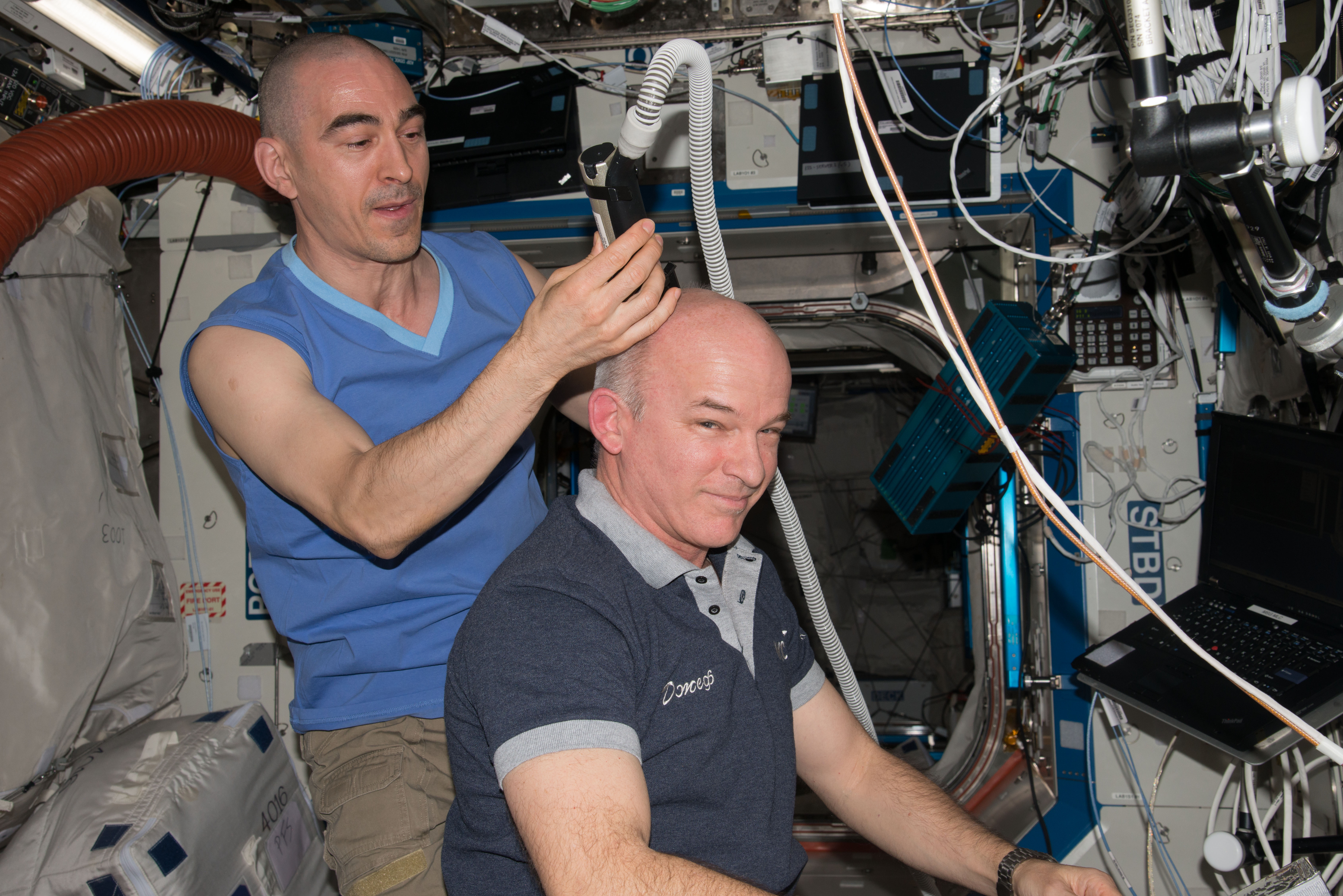 ISS048e026760 (07/16/2016) --- NASA astronaut Jeff Williams (right) gets a haircut aboard the International Space Station from Russian cosmonaut Anatoly Ivanishin (left.) The electric razor includes a vacuum hose to keep the tiny hair follicles from floating away