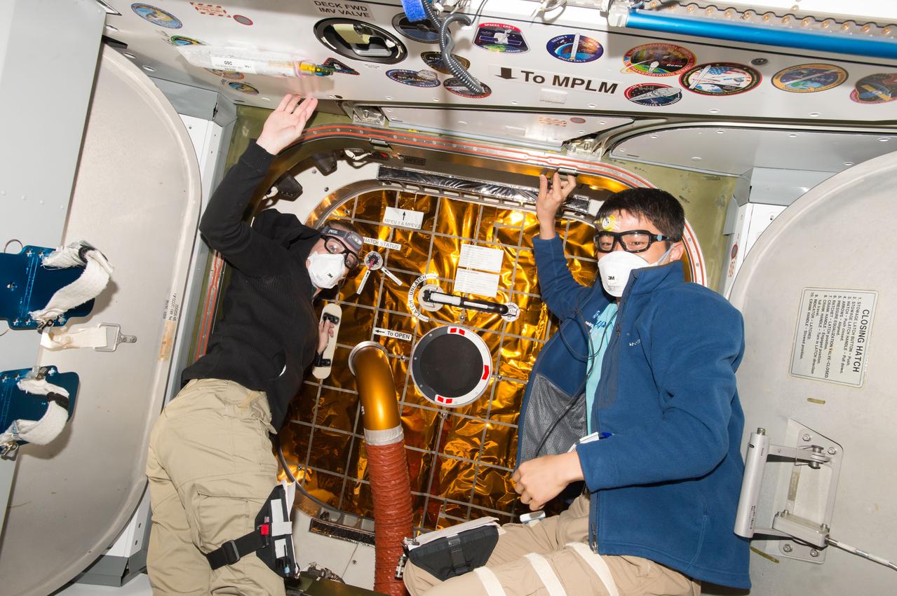 ISS048e042291 (07/20/2016) --- NASA astronaut Kate Rubins (left) and JAXA astronaut Takuya Onishi (right) prepare to open the hatch to SpaceX’s Dragon cargo spacecraft. The vehicle delivered nearly 5,000 pounds of supplies, hardware and experiments to the Expedition 48 crew. It is standard procedure for crew members to wear personal protective equipment, including masks, goggles and sometimes gloves, when entering recently arrived spacecraft. This protects them from any potential debris that may have been shaken loose during the launch and ascent phases of the flight to orbit.