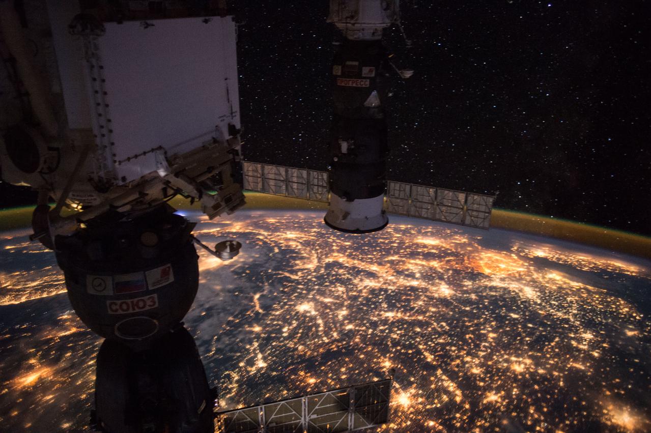 ISS049e009356 (09/24/2016) --- Earth observation taken during a night pass by the Expedition 49 crew aboard the International Space Station. Framed by the docked Soyuz and Progress spacecraft is Western Europe. The bright, dense lights in the East are the Netherlands, Belgium. The dark strip is the Alps