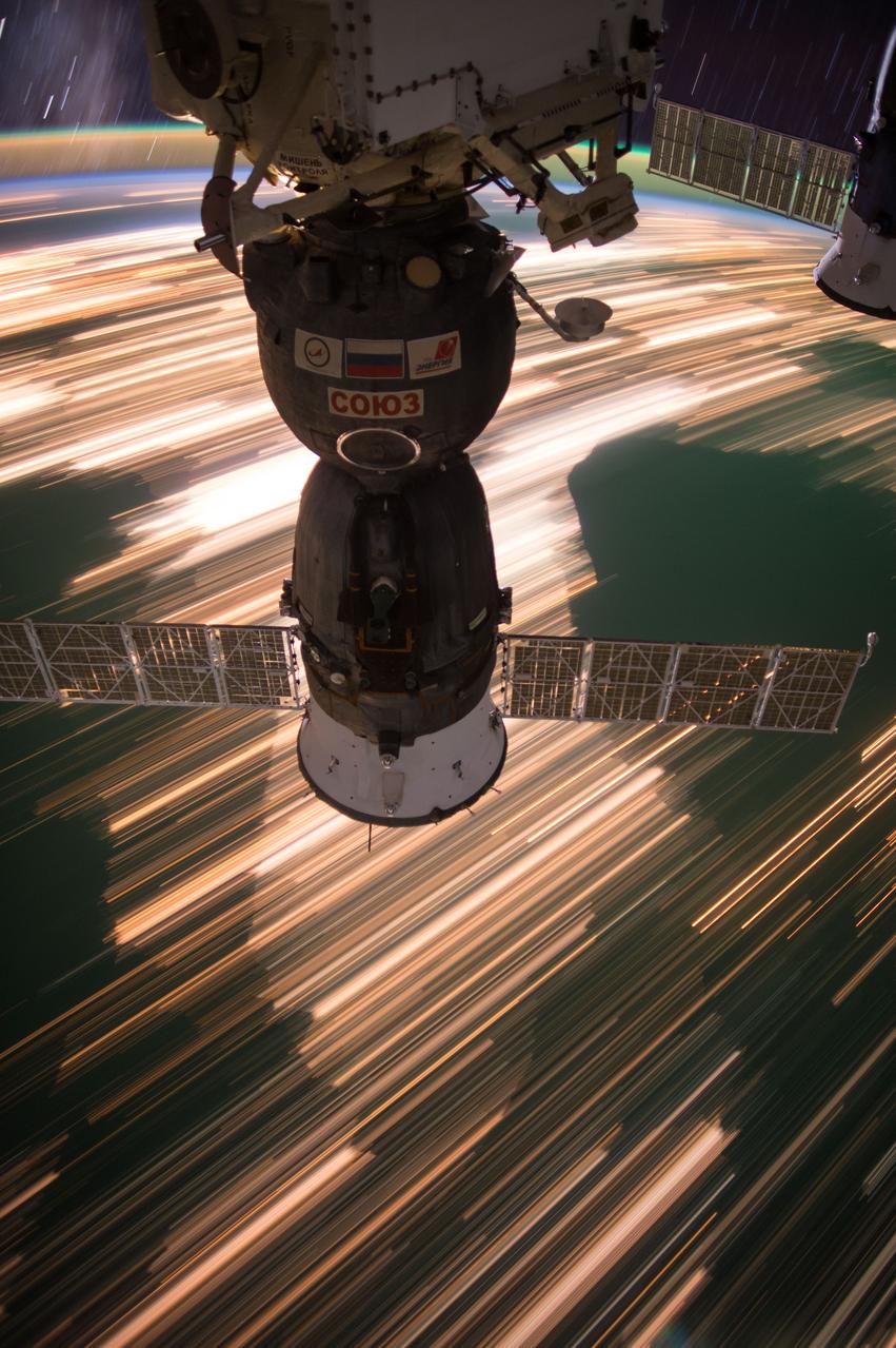 Long exposure Earth observation taken during a night pass by the Expedition 49 crew aboard the International Space Station (ISS). Stars are visible in the background. Docked Soyuz spacecraft is also visible. 