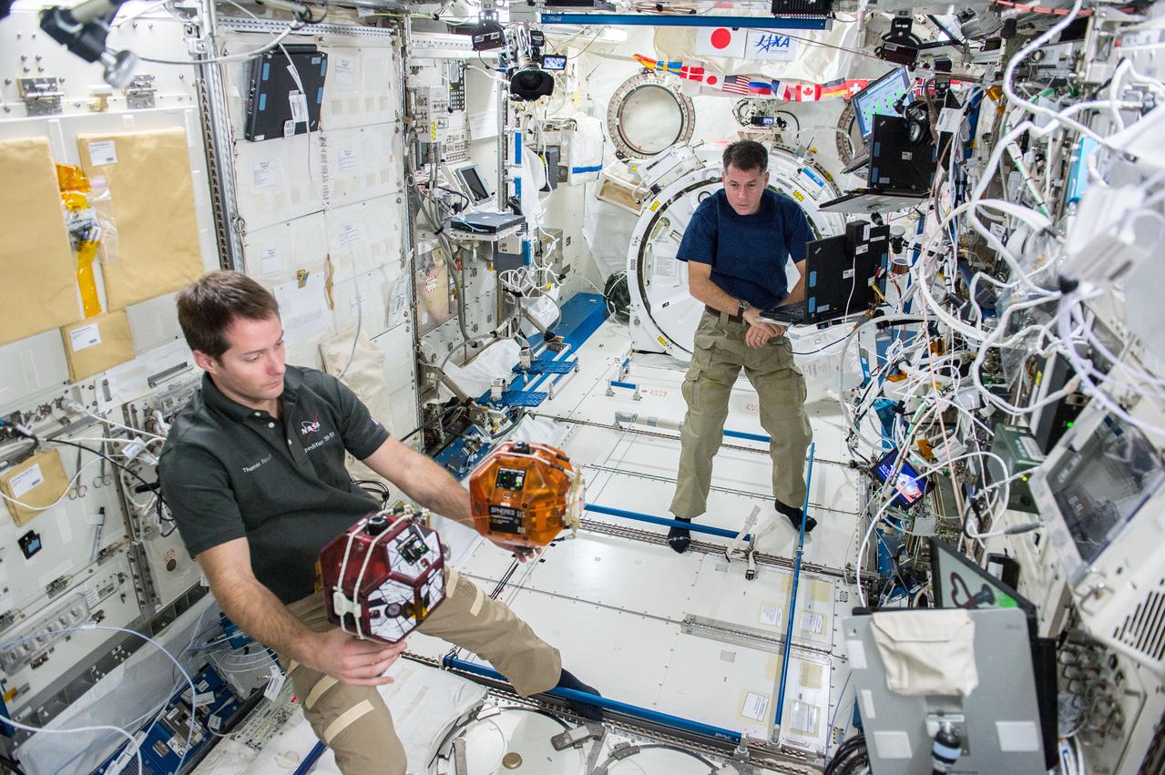 iss050e013146 (12/1/2016) --- NASA astronaut Shane Kimbrough and European Space Agency (ESA) astronaut Thomas Pesquet during the Synchronized Position Hold, Engage, Reorient, Experimental Satellites Tether Demo, in the Japanese Experiment Module (JEM) Pressurized Module (JPM). The SPHERES Tether Demo studies the dynamics of a tethered capture object and a “space tug” chase vehicle, improving computer programs needed for removing space debris as well as capturing scientific samples from other planets.